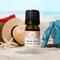Bottle of Beach Vibes Essential Oil Blend by Whole Self Aromatherapy on a beach with beach hat, flip flops, sunglasses alongside of it.